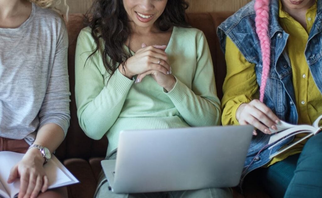 Three women sitting in front of a computer