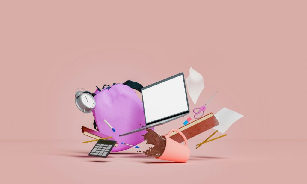 a computer, pencils, a bag, calculator and a cup of coffee flying through the air with a pink background.