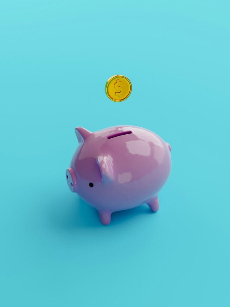 A coin dropping into a pink piggy bank. 