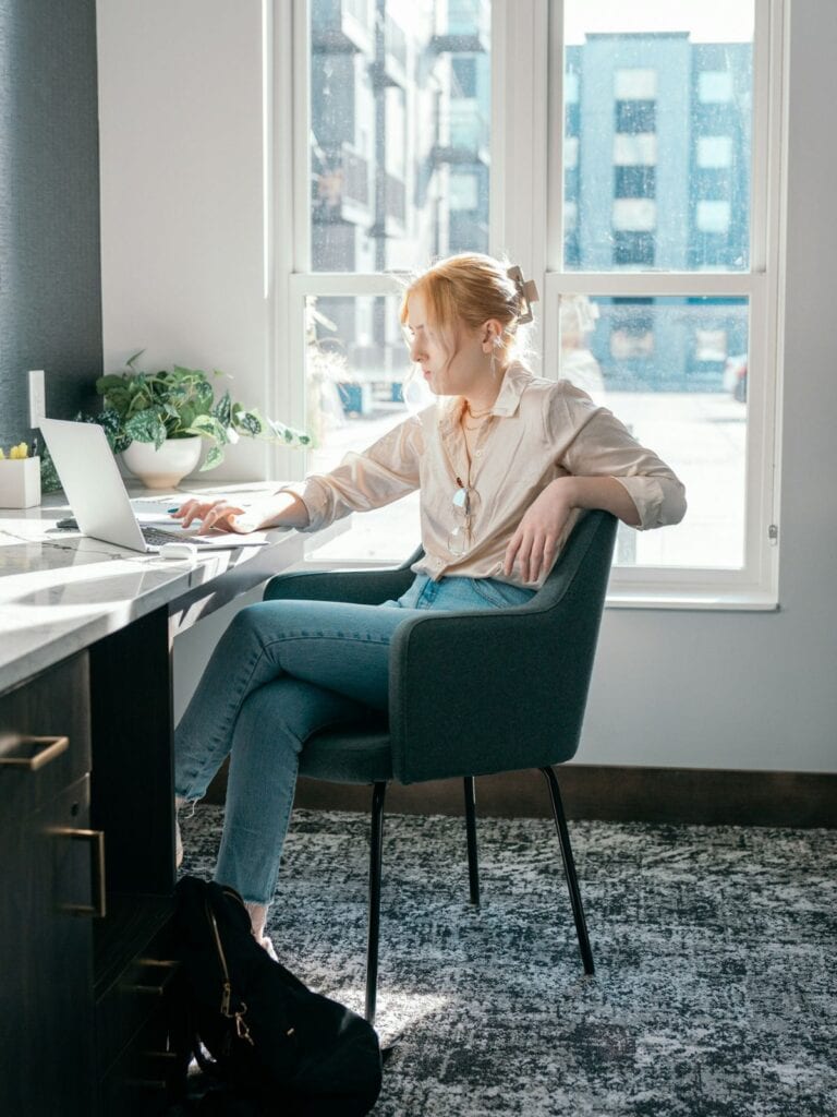 A women sitting at a desk looking at her laptop and working.