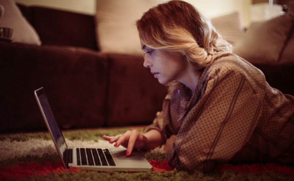 A women lying on her stomach on her laptop.