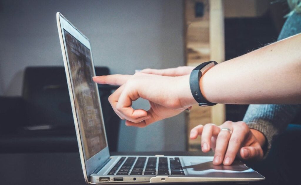 Two hands pointing at a laptop. 